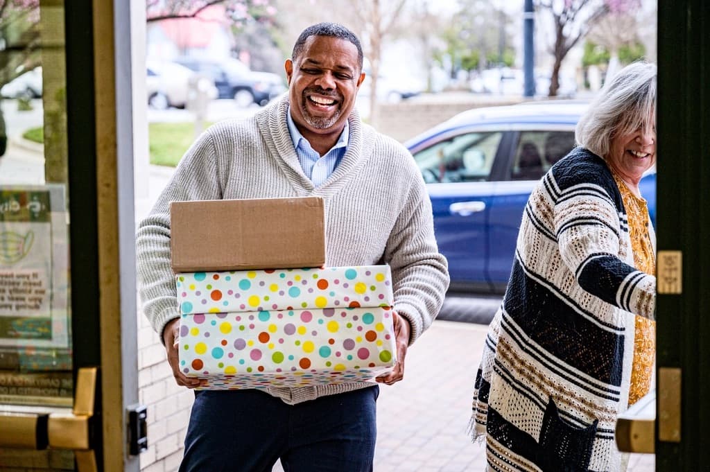 Smiling volunteer carrying donation boxes into a community centre