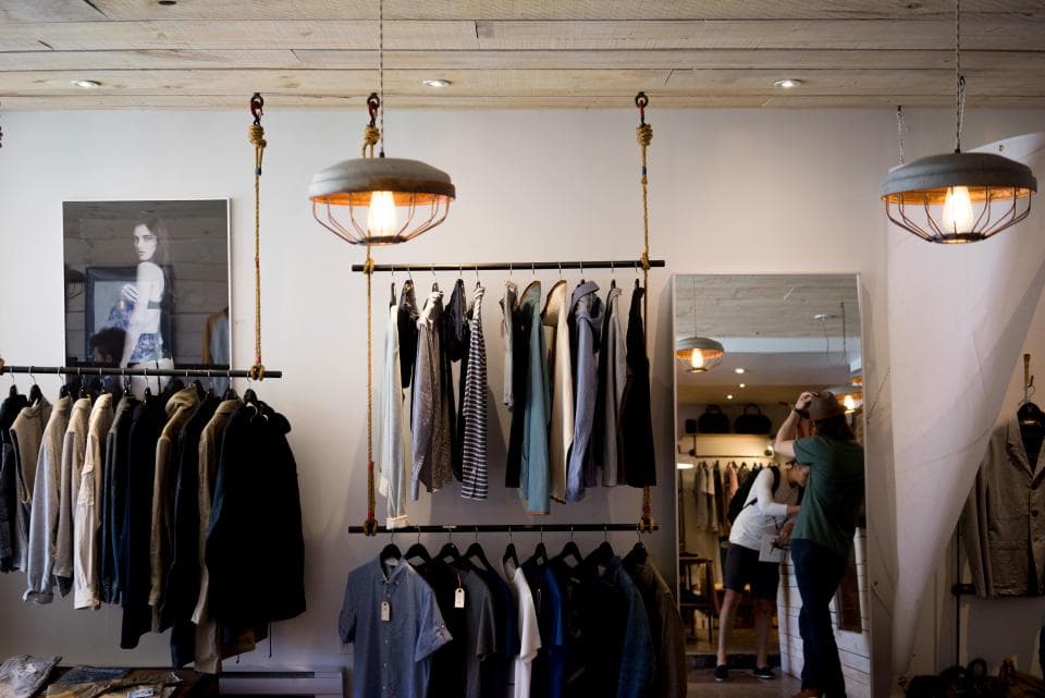Clothing store interior with racks of shirts and hanging lamps