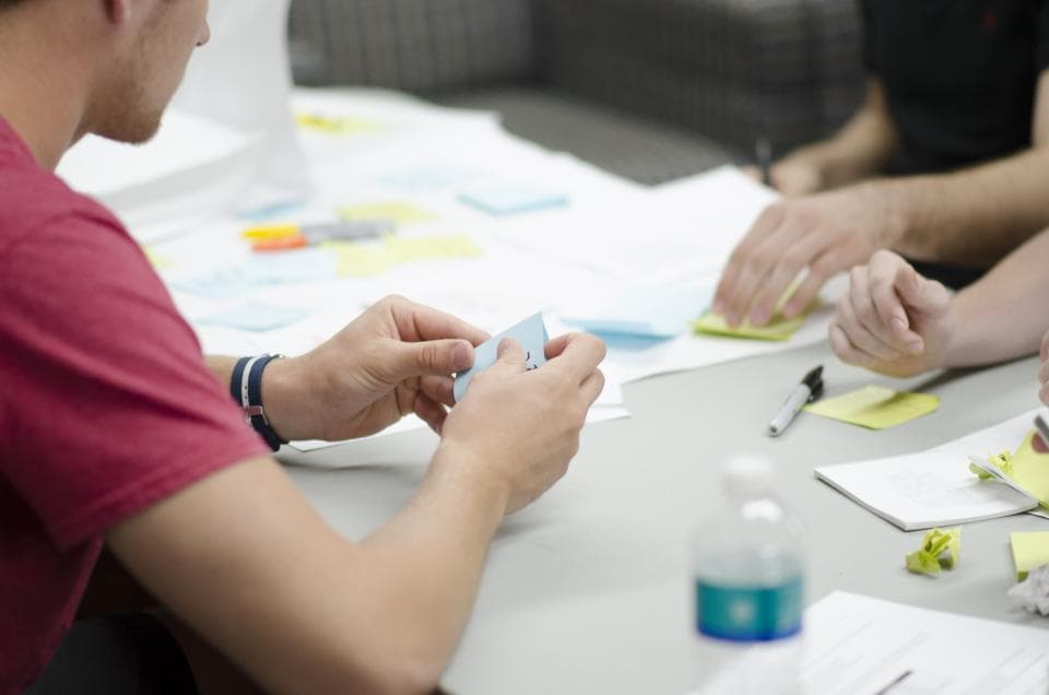Team planning a product with sticky notes and sketches on a table
