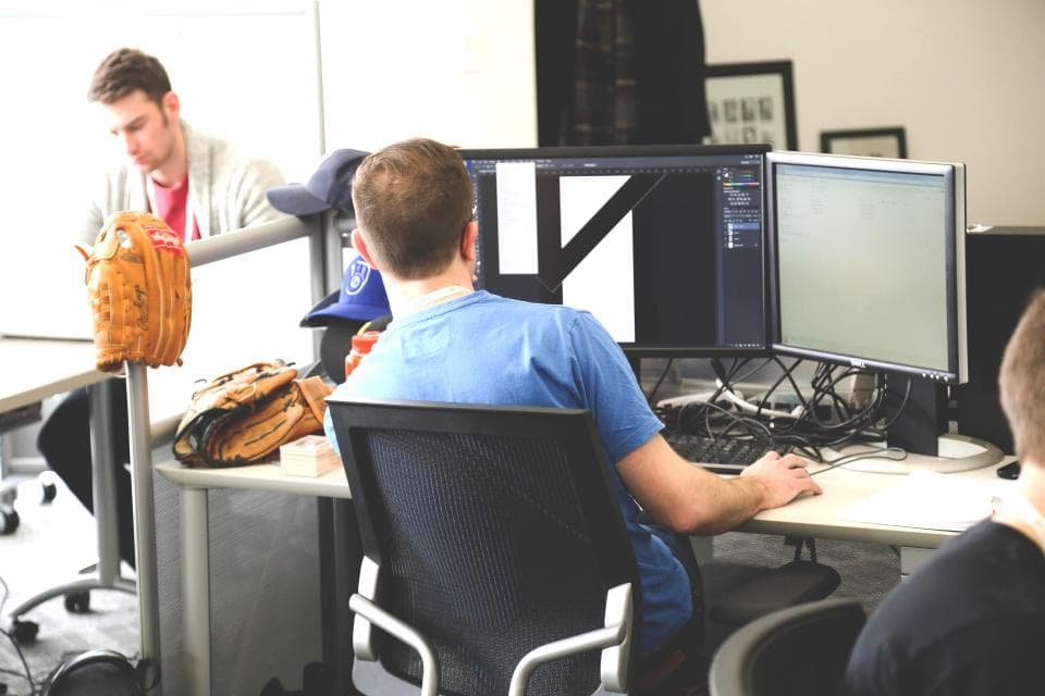Developers working at their desks with large monitors in an open office